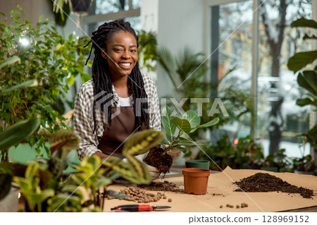 Cute african american florist planting flowers in the flower shop 128969152