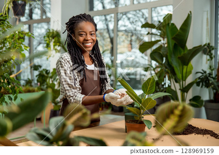 Young female florist working with plants in the flower shop 128969159