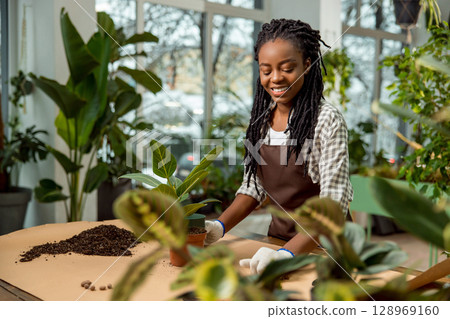 Young female florist working with plants in the flower shop Young female florist working with plants in the flower shop 128969160