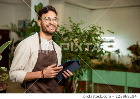 Male flower shop assistant standing with a tablet in hands 128969194