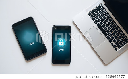 Two Mobile Devices Displaying VPN Icons with a Laptop on a White Surface 128969577