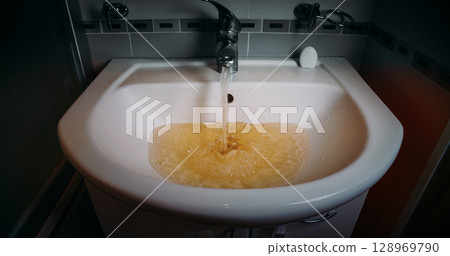 Basin overflowing with yellow tinted water Basin overflowing with yellow tinted water 128969790