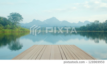 Wooden pier extending into a serene lake, reflecting the surrounding lush vegetation and distant mountains, creating a tranquil and inviting atmosphere perfect for relaxation and enjoying nature Wooden pier extending into a serene lake, reflecting the surrounding lush vegetation and distant mountains, creating a tranquil and inviting atmosphere perfect for relaxation and enjoying nature 128969950