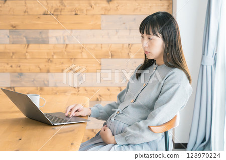 A pregnant woman working from home in the living room A pregnant woman working from home in the living room 128970224
