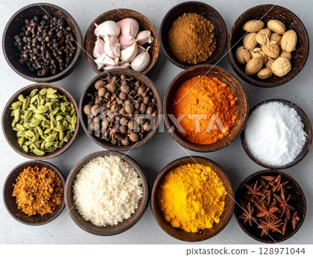 Assorted Aromatic Spices in Wooden Bowls Displayed on a Gray Surface Flatlay 128971044