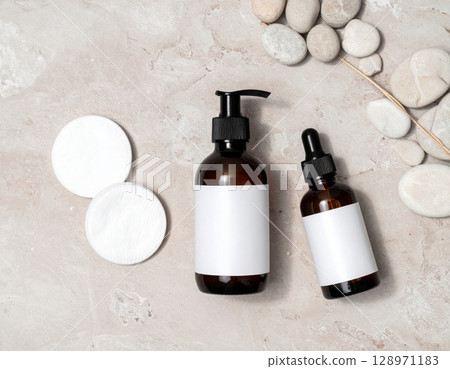 Elegant Amber Glass Skincare Bottles with Blank Labels and Stone Adornment on Beige Backdrop Elegant Amber Glass Skincare Bottles with Blank Labels and Stone Adornment on Beige Backdrop 128971183