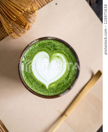 Matcha Latte in Bowl with Heart Foam and Bamboo Utensils on Rustic Table 128971638