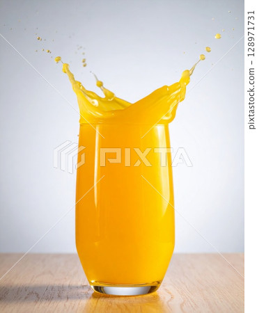 Tall Glass of Refreshing Orange Juice Splashing on a Wood Table Against White Backdrop 128971731