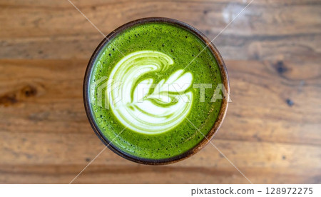 Close up of Bright Green Matcha Latte Art on a Wood Grain Table Top 128972275