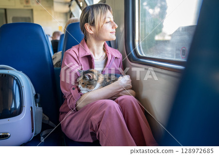 Relaxed calm cat riding in happy woman hands travels on train. Pet comfort accustomed to journeys Relaxed calm cat riding in happy woman hands travels on train. Pet comfort accustomed to journeys 128972685