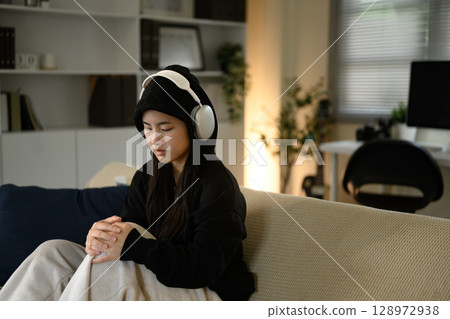 Sad teenage girl sitting quietly with headphones on at home. Mental health concept 128972938