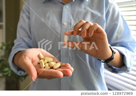 Close up of person holding nutritional supplements. Healthcare and wellness concept Close up of person holding nutritional supplements. Healthcare and wellness concept 128972969