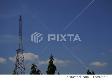 view of blue sky and communication towers and trees 128973580