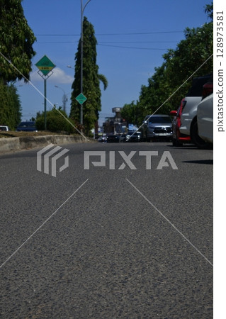 view of city streets and trees and parked vehicles 128973581