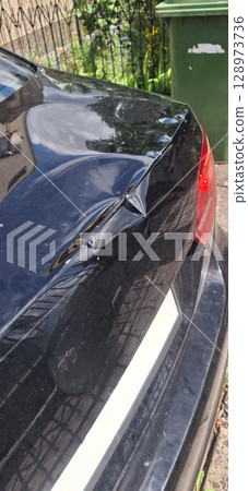 Black Car Rear Panel Damage Dent Repair Automotive Body Work Green Bin Curb Side Outdoor Sunlight Detail Texture 128973736