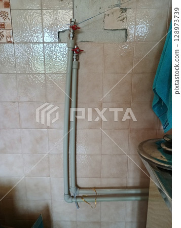 Water Pipe Installation with Valves Under Bathroom Sink: Close-Up Shot of Plumbing Fixtures, Beige Tiles, and Modern Home Renovation Works Water Pipe Installation with Valves Under Bathroom Sink: Close-Up Shot of Plumbing Fixtures, Beige Tiles, and Modern Home Renovation Works 128973739