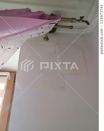 Interior Corner Showing Repaired Wall Patch, Drapery Fabric, Brass Candle Holders, and Light Pink Color Scheme. Home Renovation and Decoration Scene 128973741