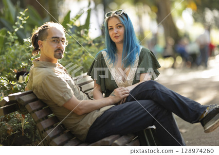 Young couple relaxing on bench in park with pet rat 128974260