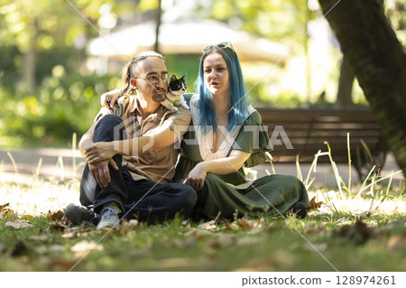 Young couple relaxing in park with kitten on man's shoulder 128974261