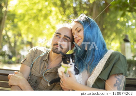 Young couple holding a kitten are enjoying a sunny day in the park 128974262