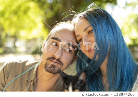 Young couple relaxing outdoors with pet cat in summer 128974263