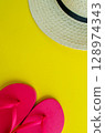 Flatlay, summer vacation. Hat and sandals on a yellow background. Vertical background. 128974343