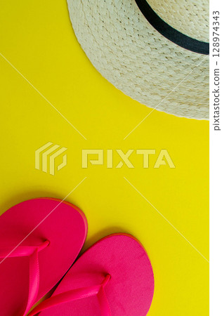 Flatlay, summer vacation. Hat and sandals on a yellow background. Vertical background. Flatlay, summer vacation. Hat and sandals on a yellow background. Vertical background. 128974343