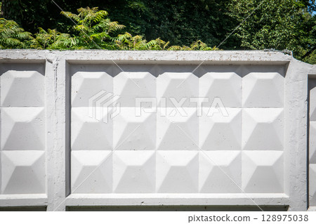 Geometric Concrete Fence Panel with Sunlight and Nature in Background Geometric Concrete Fence Panel with Sunlight and Nature in Background 128975038