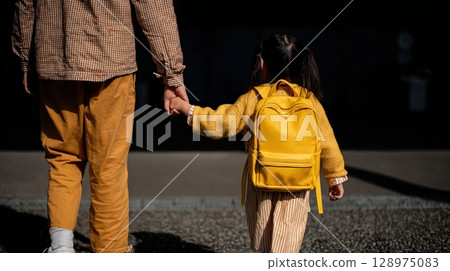 child with school backpack is holding hands mother's 128975083