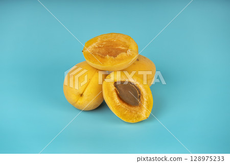 Juicy apricots with visible seed placed on vibrant blue background. 128975233