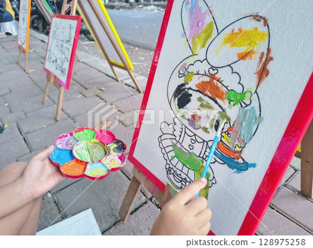 child paints a colorful picture with colorful 128975258