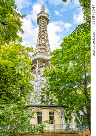 Petrin Lookout Tower rises above the lush trees, offering stunning views of Prague. Visitors enjoy the vibrant surroundings while climbing to the observation deck for breathtaking scenery. Petrin Lookout Tower rises above the lush trees, offering stunning views of Prague. Visitors enjoy the vibrant surroundings while climbing to the observation deck for breathtaking scenery. 128975544