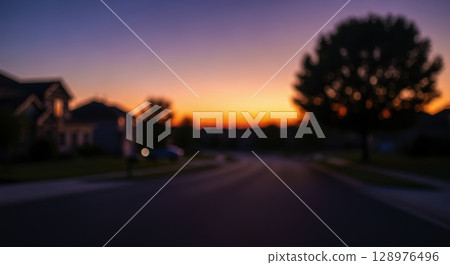 Blurred suburban street at dusk with warm sunset sky and soft focus bokeh effect 128976496