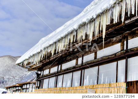 A winter scene with sharp icicles hanging from the eaves A winter scene with sharp icicles hanging from the eaves 128977194