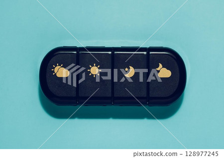 Daily Pill Organizer with Sun and Moon Icons on Blue Daily Pill Organizer with Sun and Moon Icons on Blue 128977245