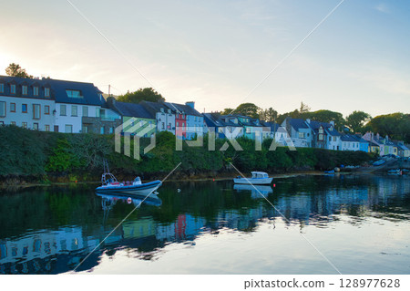 Picturesque coastal village in Ireland with colorful buildings, boats, and reflections in calm water. Picturesque coastal village in Ireland with colorful buildings, boats, and reflections in calm water. 128977628