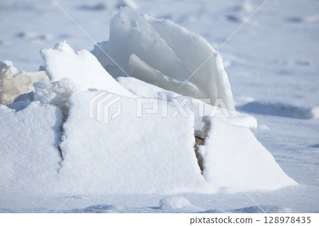 Snow-Covered Frozen Surface with Natural Ice Structures in Winter Landscape 128978435