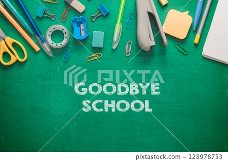 A green chalkboard with a variety of school supplies 128978753