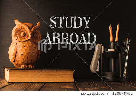 A wooden owl sits on top of a stack of books A wooden owl sits on top of a stack of books 128978792