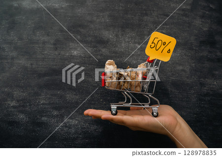 A hand holding a shopping cart with a 50 sign on it 128978835