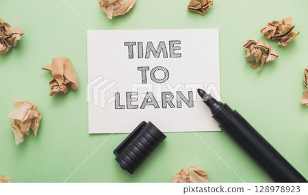 A marker is on a piece of paper that says Time to learn. 128978923
