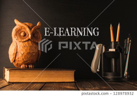 A wooden owl sits on top of a stack of books A wooden owl sits on top of a stack of books 128978932