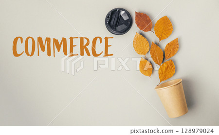 A leafy plant is in a paper cup with the word COMMERCE written on it 128979024