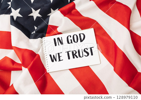 Red and white American flag with a white sign that says In God We Trust Red and white American flag with a white sign that says In God We Trust 128979110