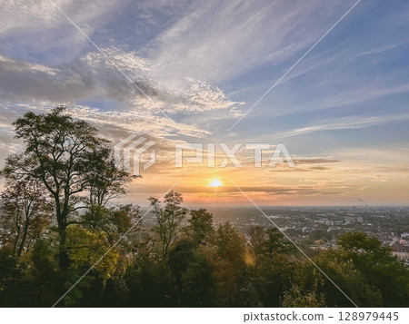 The sky is blue with a few clouds and the sun is setting The sky is blue with a few clouds and the sun is setting 128979445