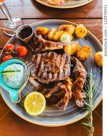 Plate of food with meat and potatoes, garnished with lemon and herbs 128979451