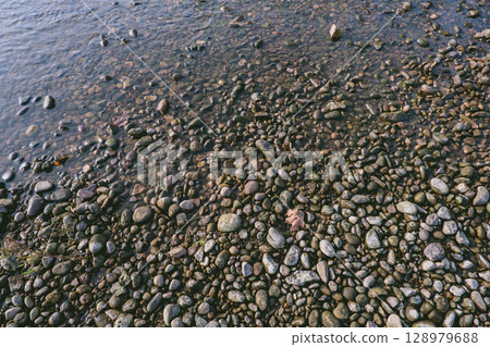 Rocky shoreline with a body of water in the background 128979688