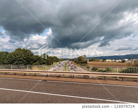 Highway with a bridge over it and a cloudy sky 128979724