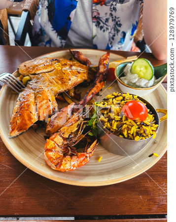 Plate of food with a chicken, shrimp, and rice Plate of food with a chicken, shrimp, and rice 128979769