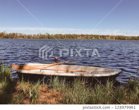A small boat sits in the water with a paddle in the front 128979961